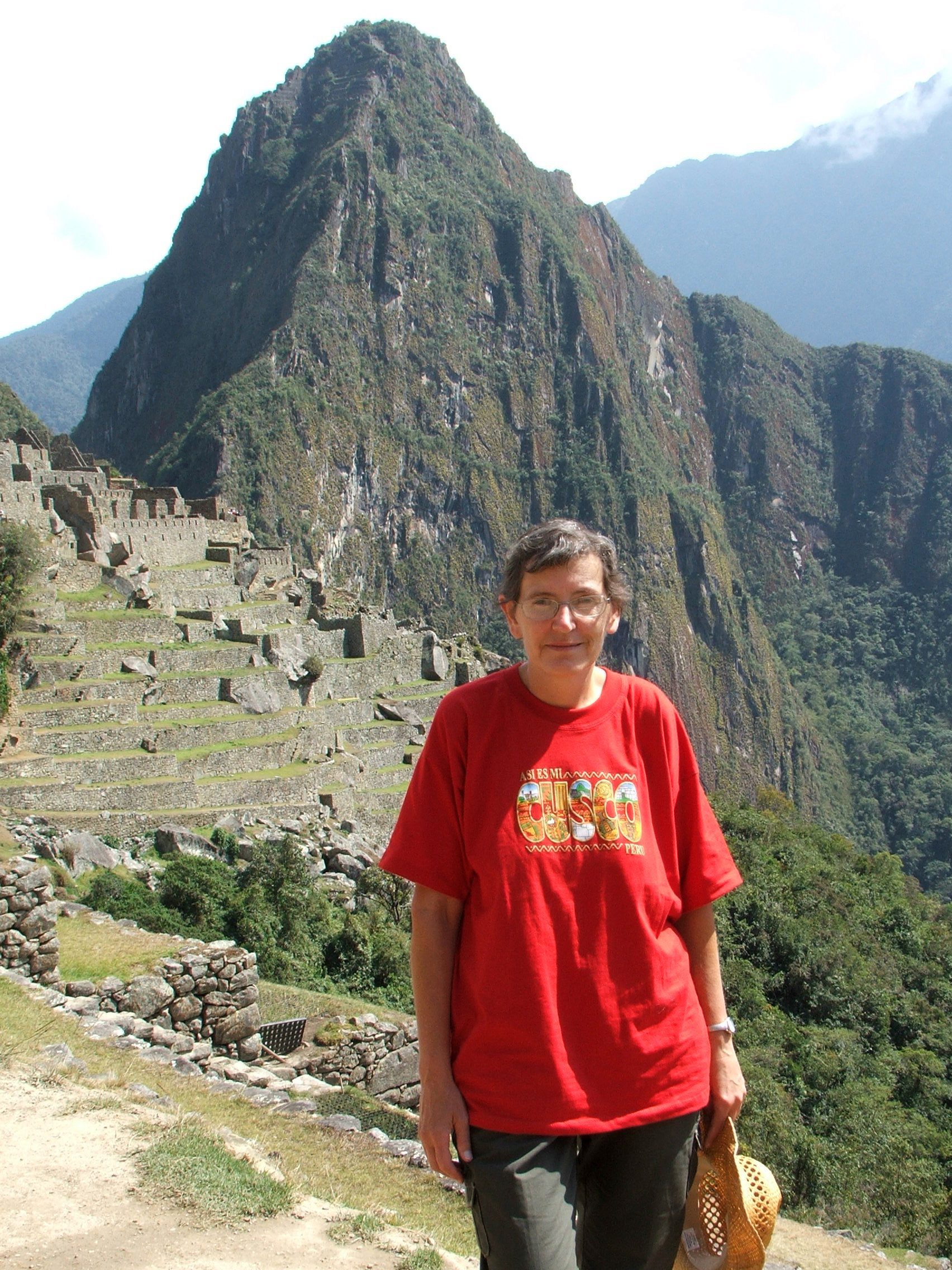 Karen Watson standing in front of a larger mountain and ancient village.